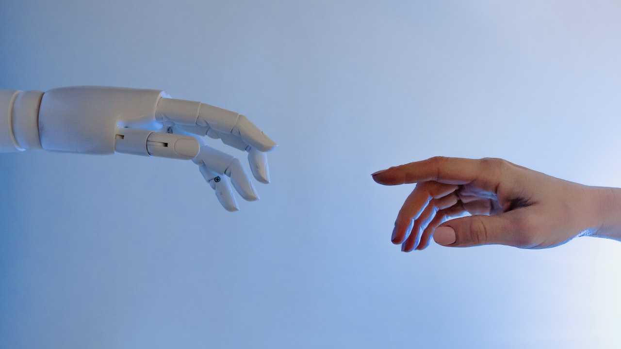 A machine hand reaches out to a human hand.