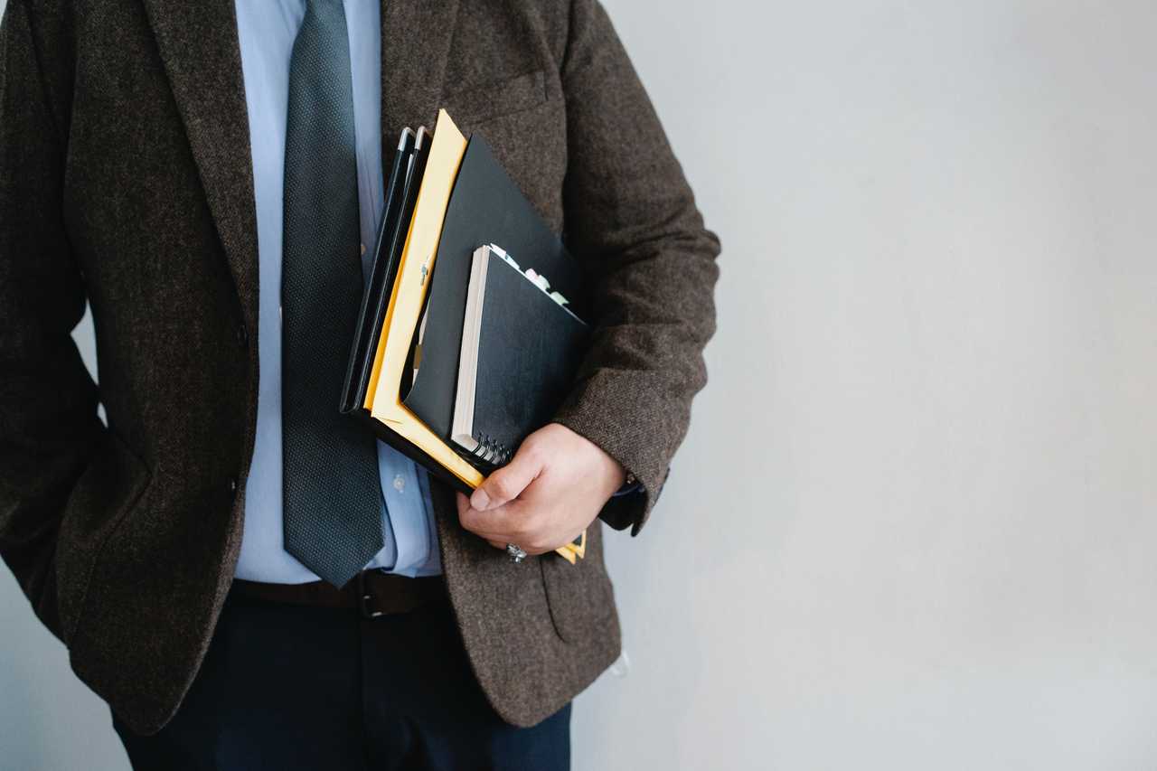 Image of a businessman in a suite carrying folders with paperwork